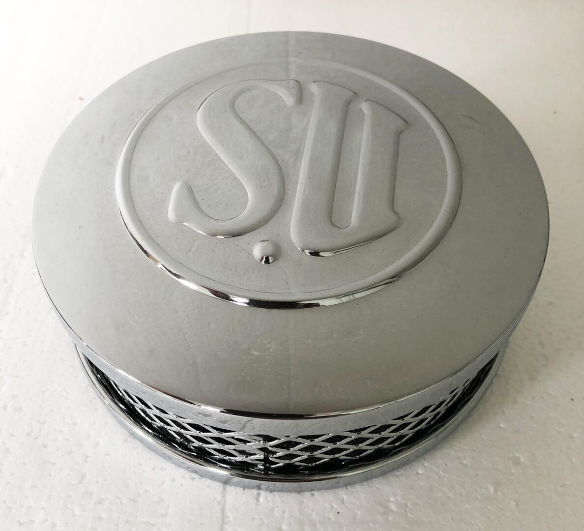 A chrome air cleaner with the letters su on it.