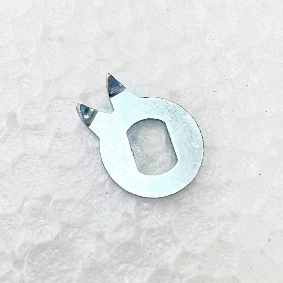 A metal piece of material with two small holes.
