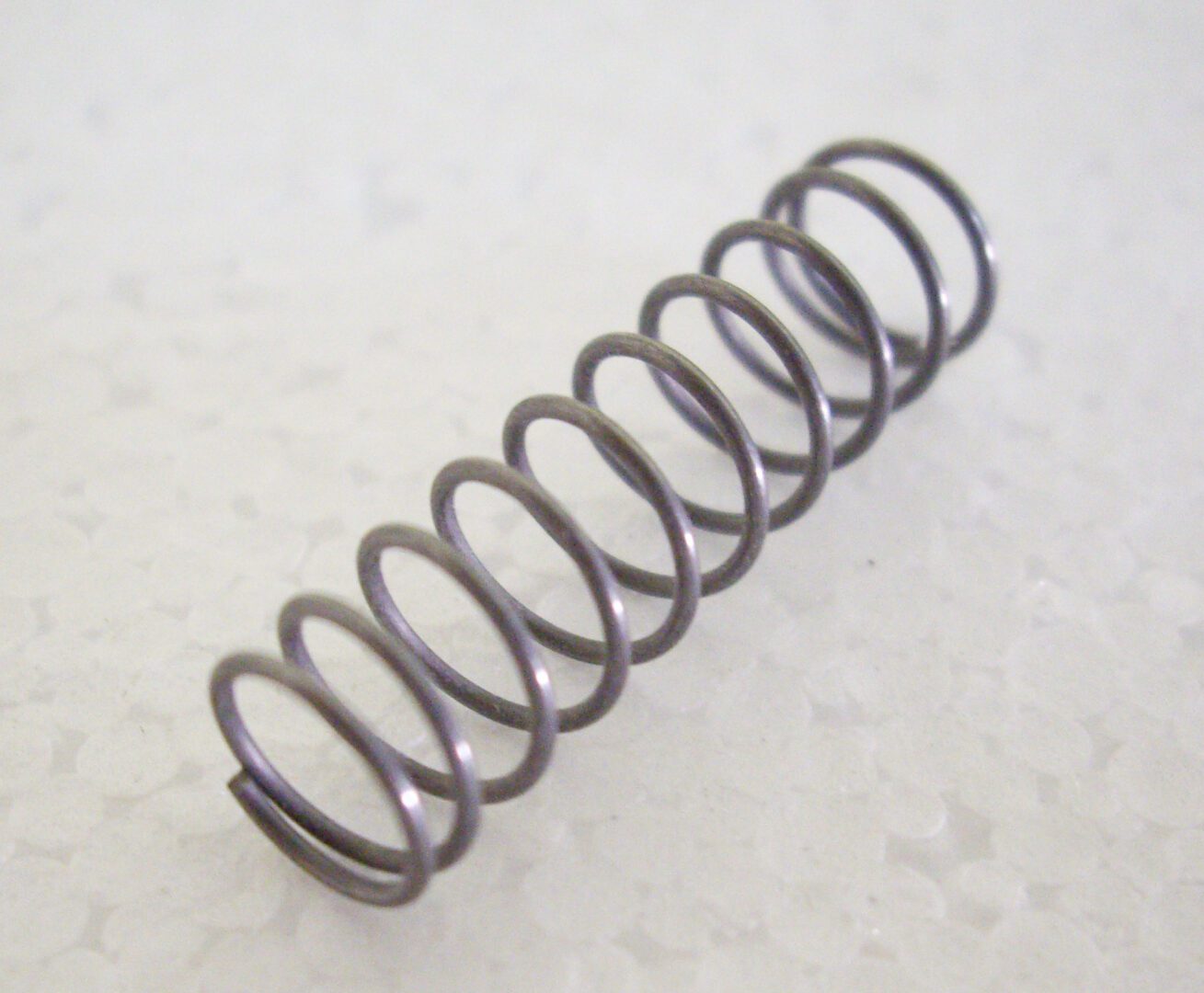 A metal spring sitting on top of a white surface.