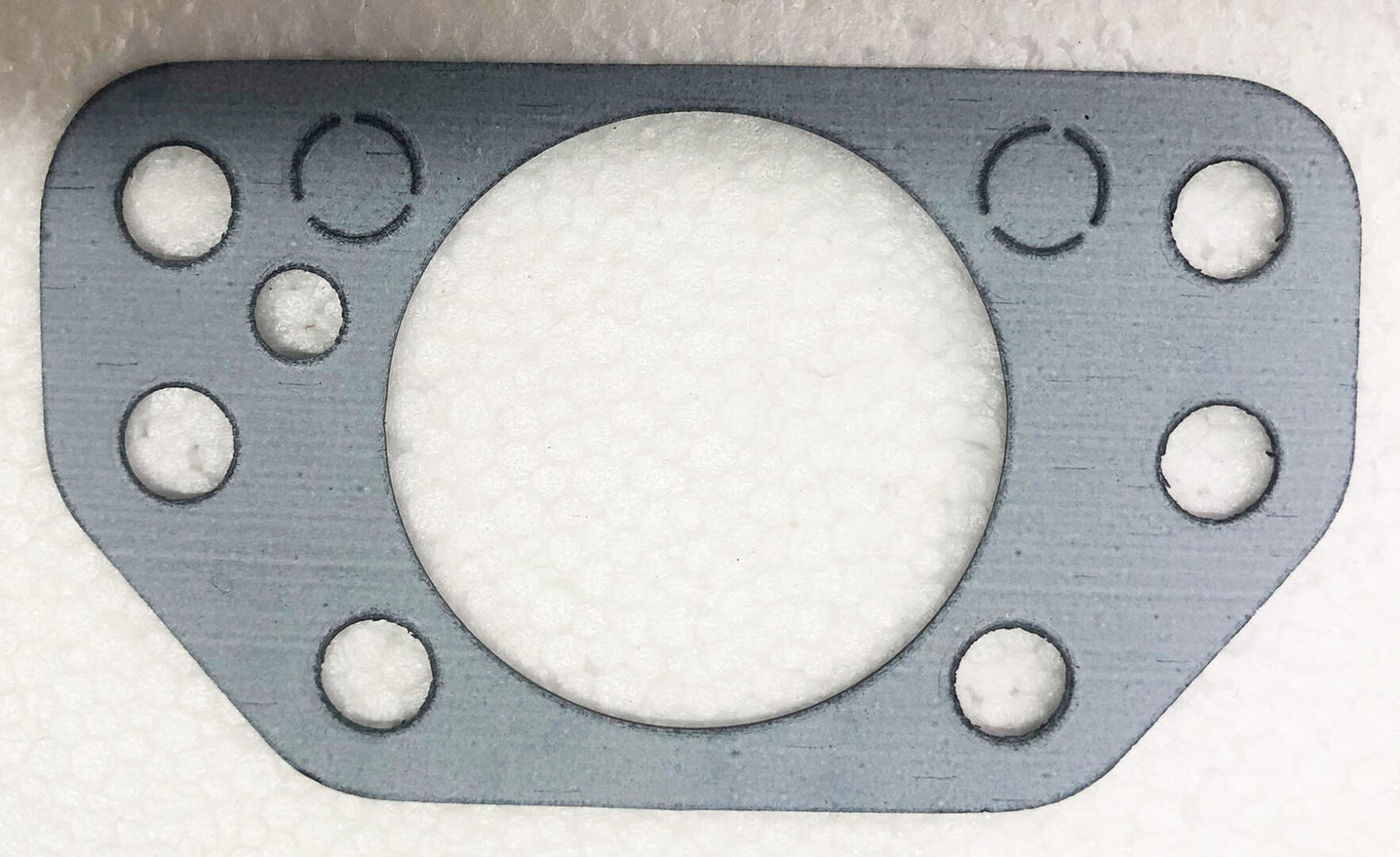 A metal gasket with four holes for the valve.