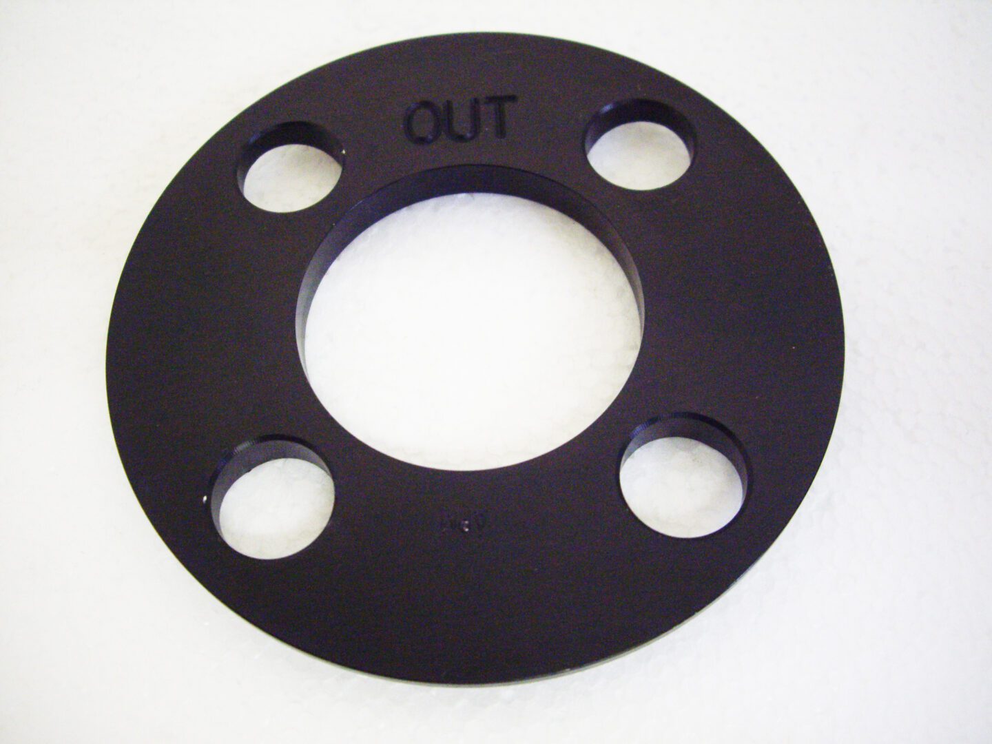 A black plastic disc with four holes on it.