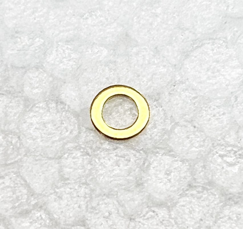 A gold colored washer sitting on top of white fabric.