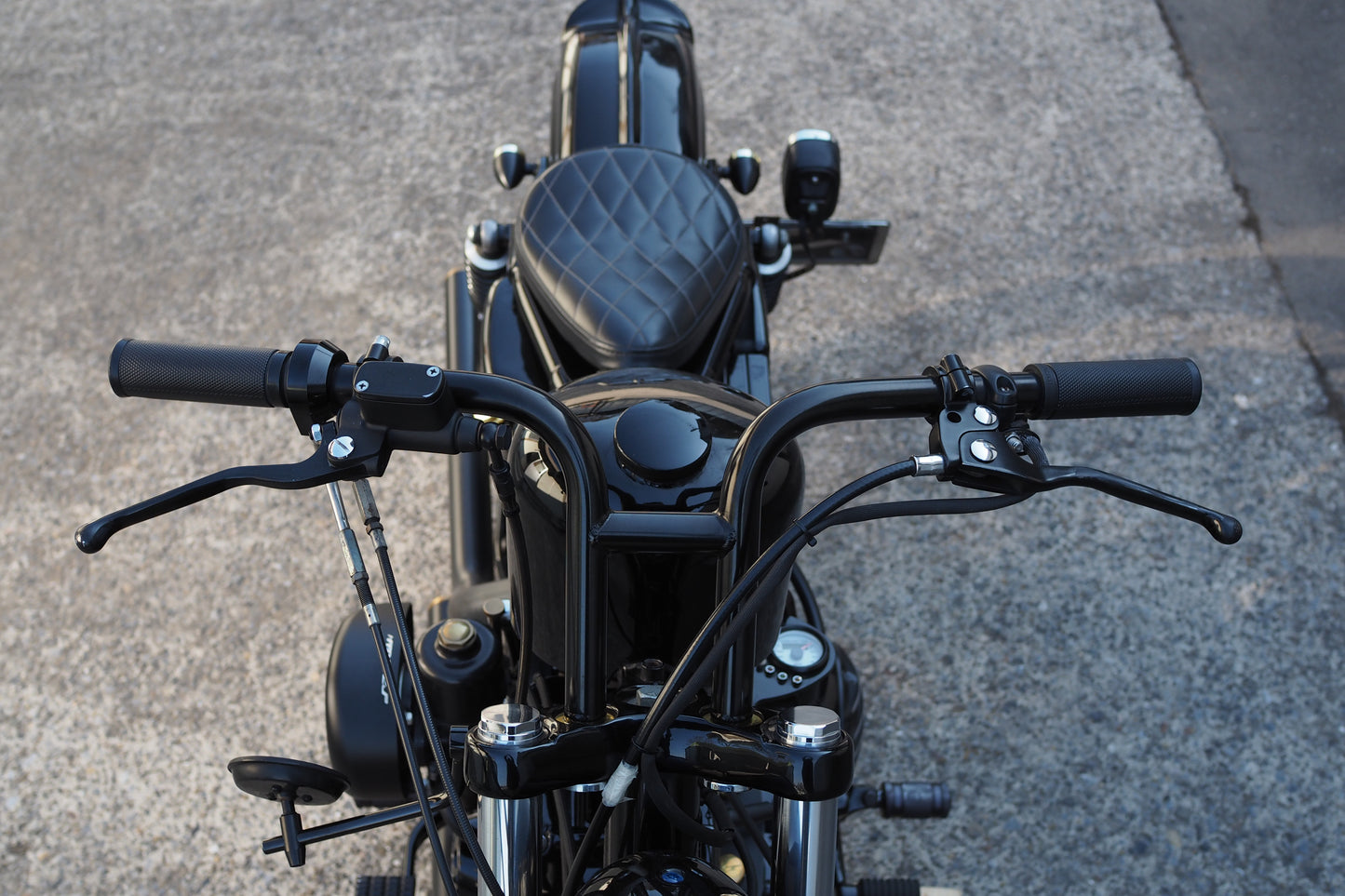 A motorcycle is parked on the street with its handlebars.