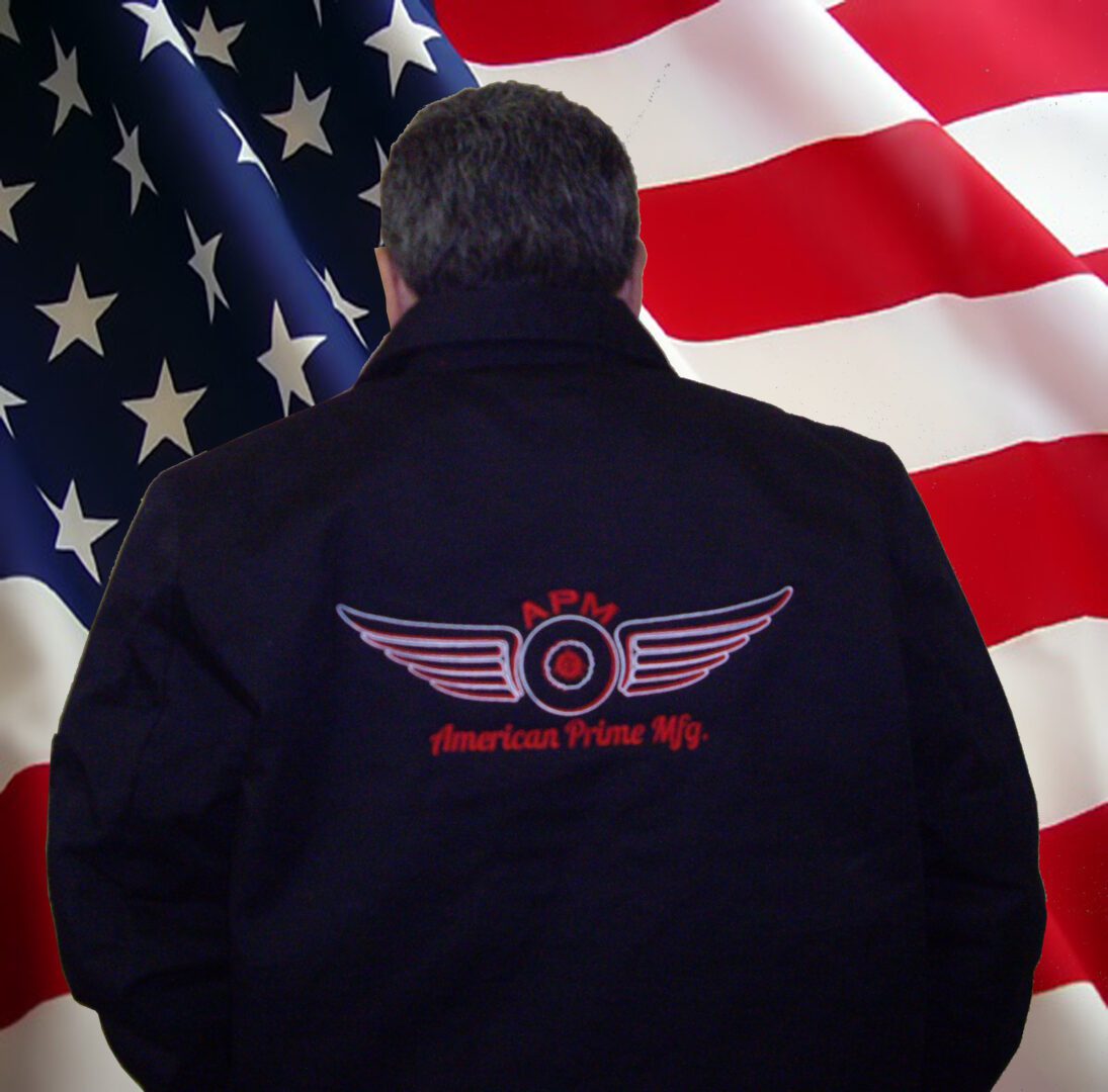 A man in a black jacket standing next to an american flag.