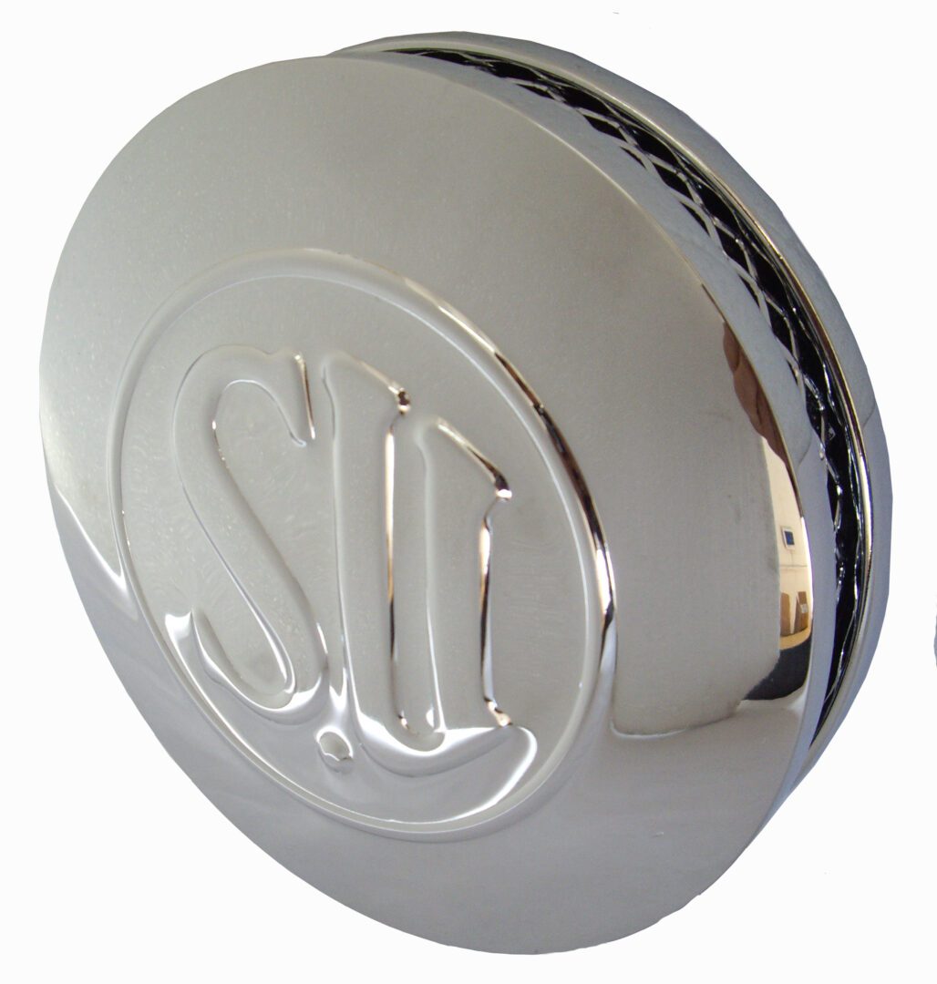 A chrome round shaped knob with the letters s and t on it.