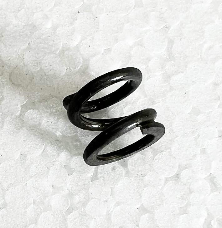 A black metal spiral spring sitting on top of white paper.