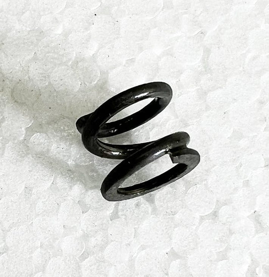 A black metal spiral spring sitting on top of white paper.