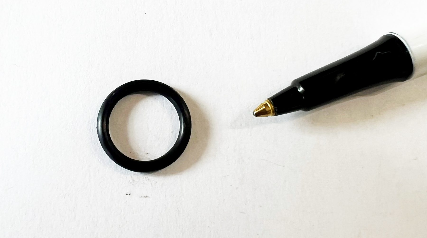 A black ring and a pen on top of a table.