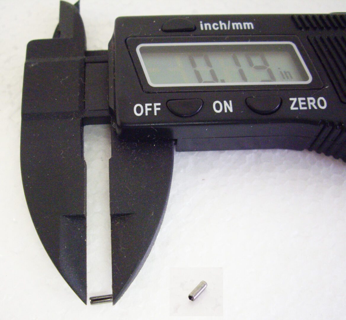 A digital caliper with a small piece of metal in front.