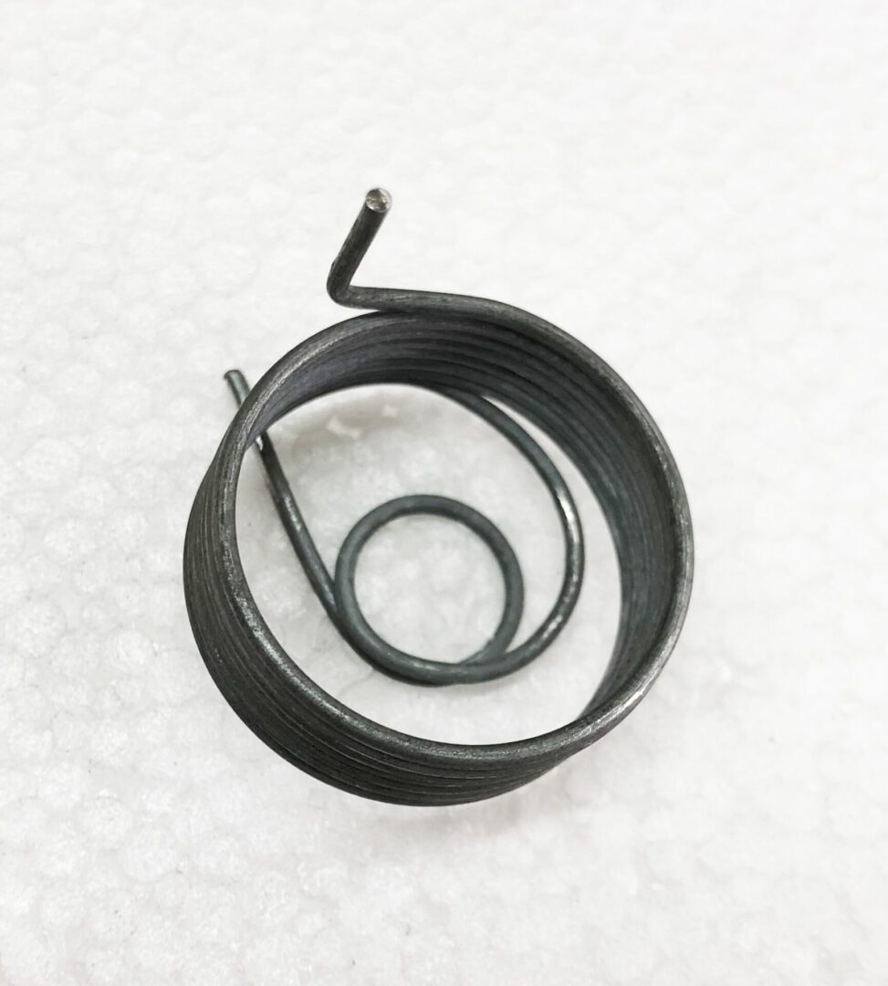 A metal coil sitting on top of a white surface.