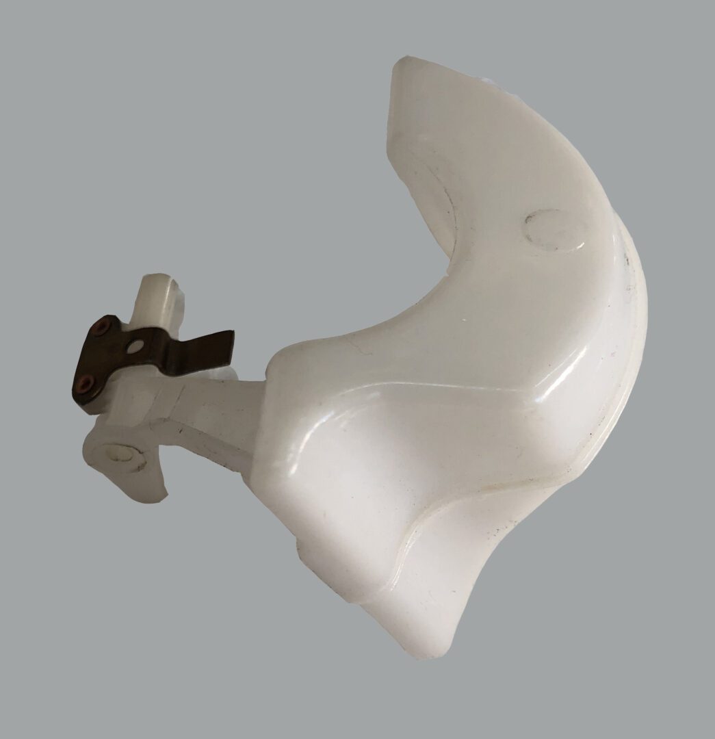 A white plastic object with brown handle and gray background