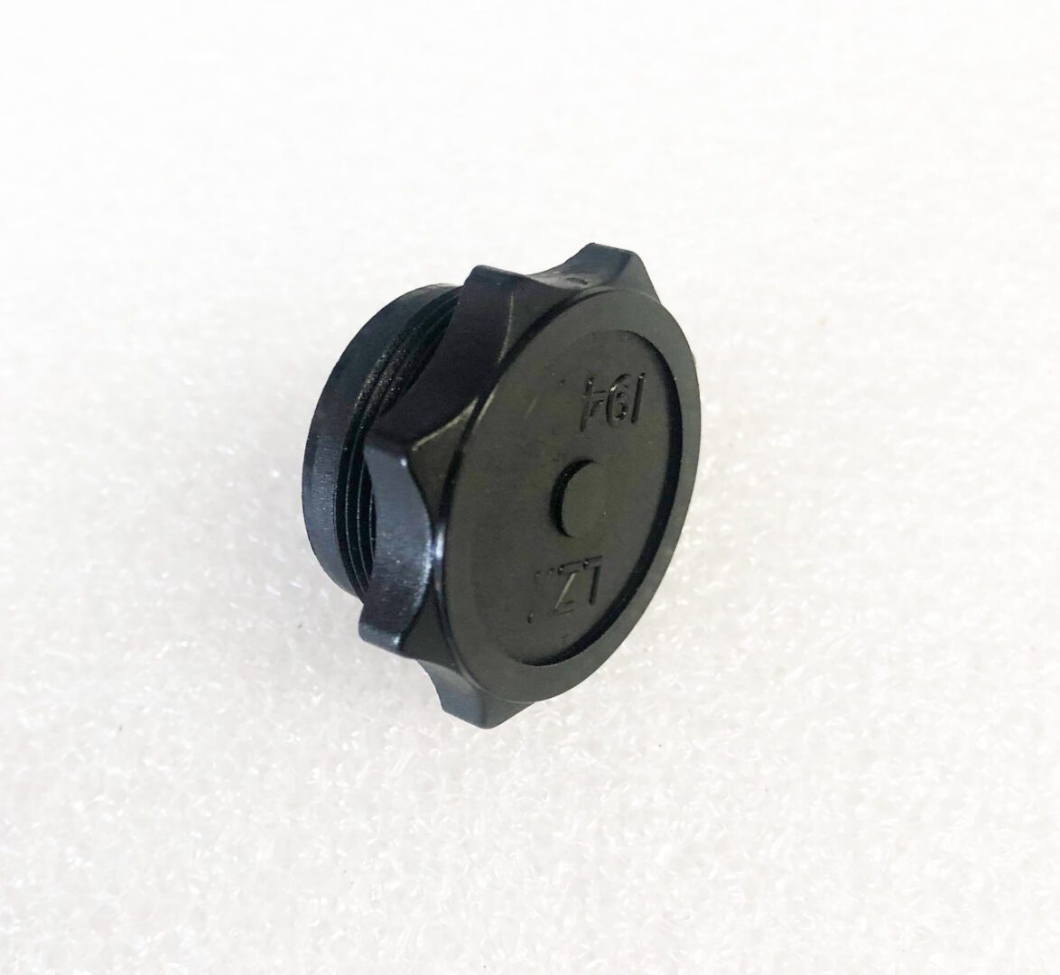 A black plastic cap sitting on top of a white table.