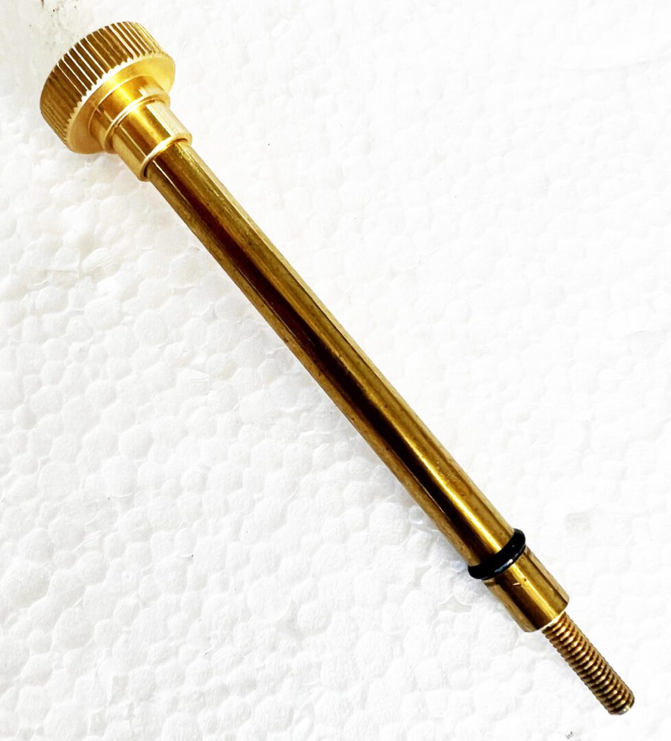 A gold colored handle with black rubber on top of it.