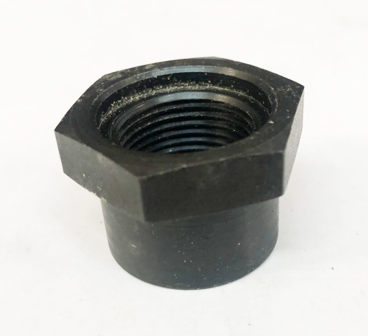 A black nut is sitting on top of the floor.