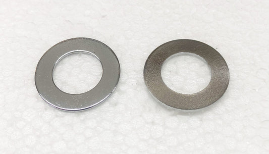 A pair of metal washers sitting on top of white paper.