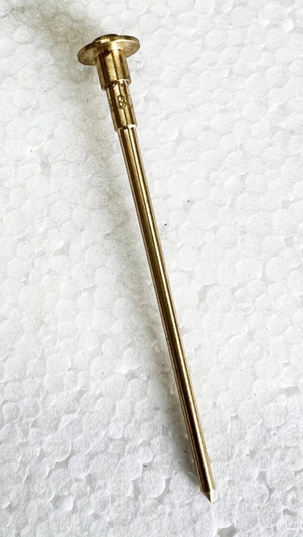 A gold colored metal stick with a white background