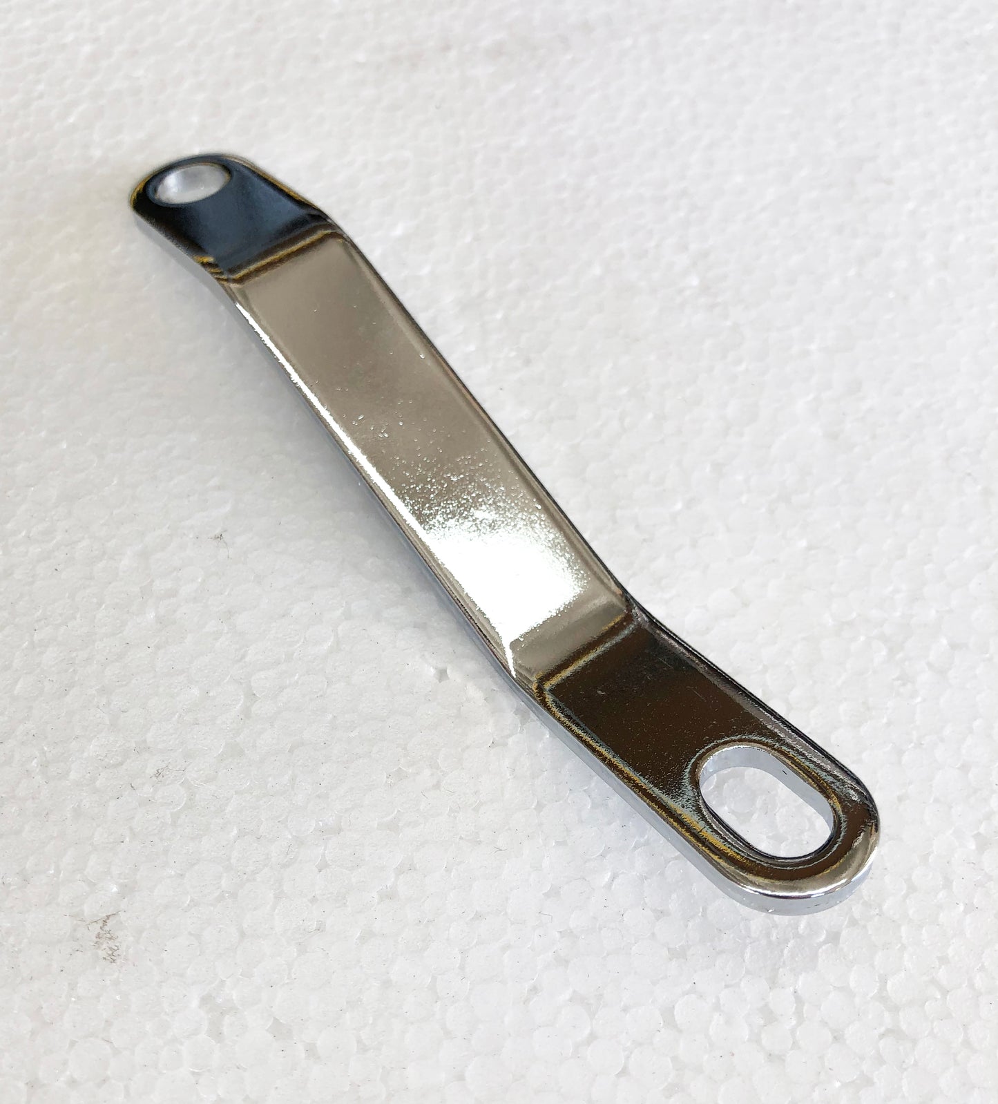 A metal wrench sitting on top of a white surface.