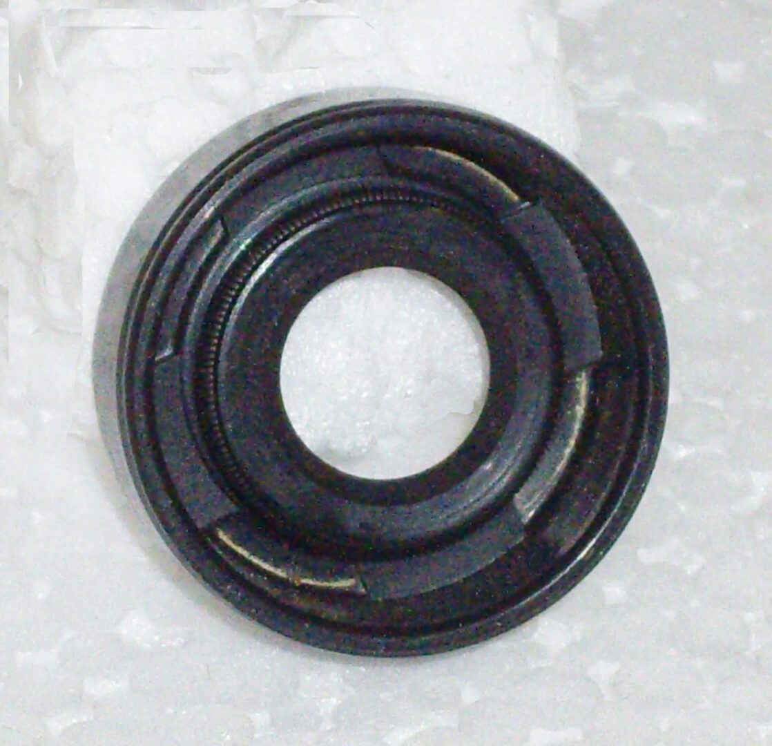 A black rubber seal sitting on top of a white surface.