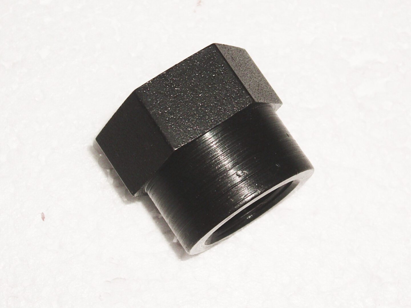 A black nut is sitting on the floor.