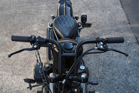 A motorcycle is parked on the street with its handlebars.